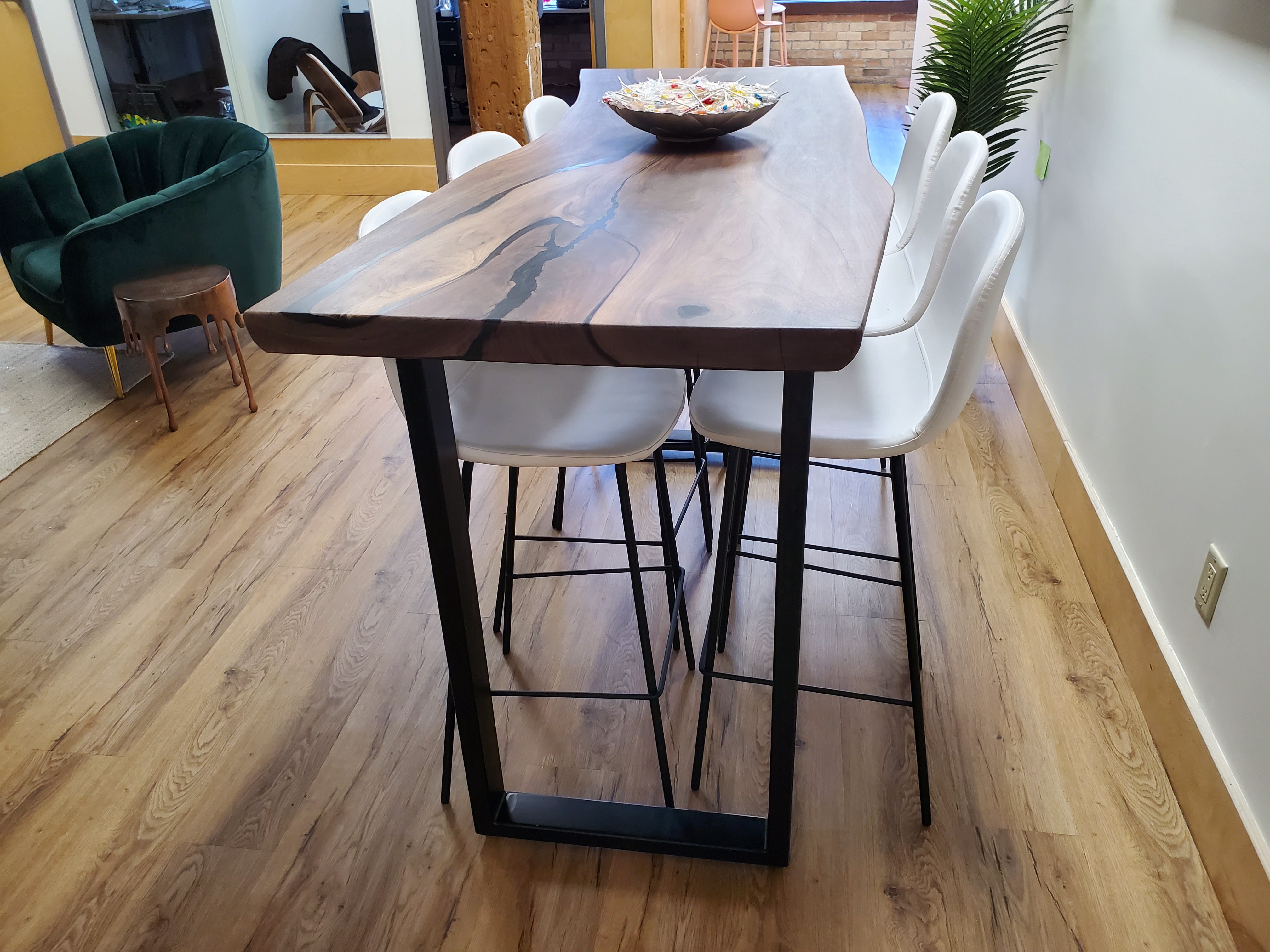 Live-edge hardwood dining table with white chairs in a warm residential interior.