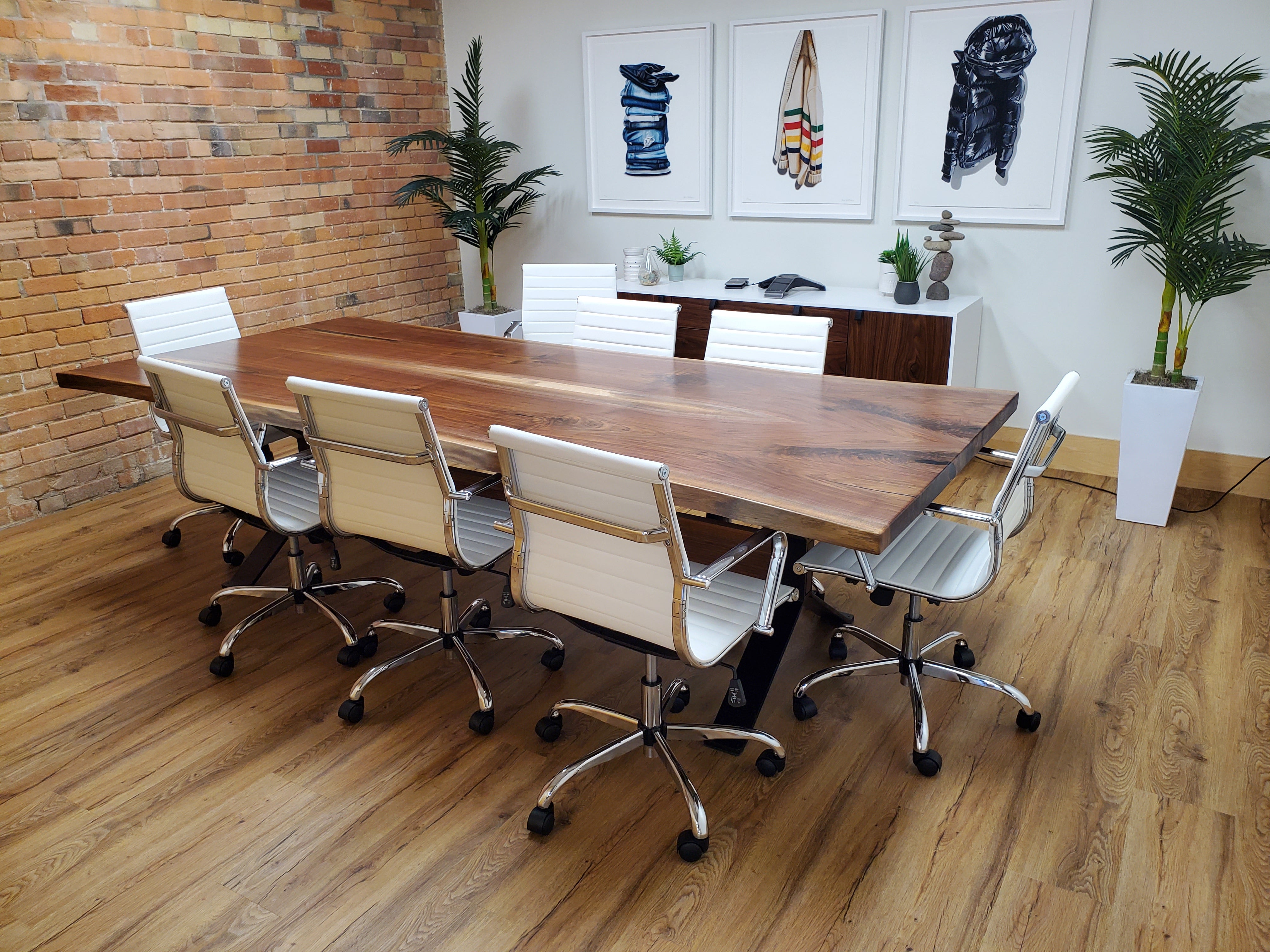 Large solid hardwood boardroom table surrounded by white office chairs in a modern meeting room.