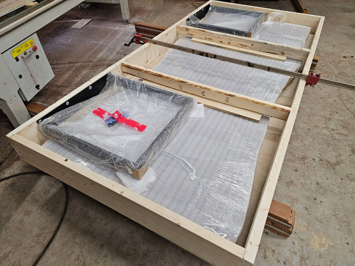 The protected walnut tabletop and separately secured steel legs inside the open shipping crate.