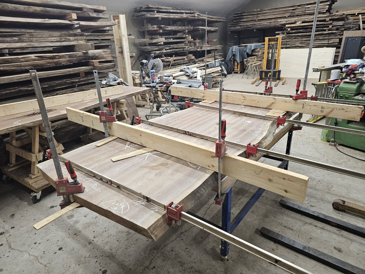 The two selected walnut slabs held in clamps during glue-up in the Beaver Hardwood studio.
