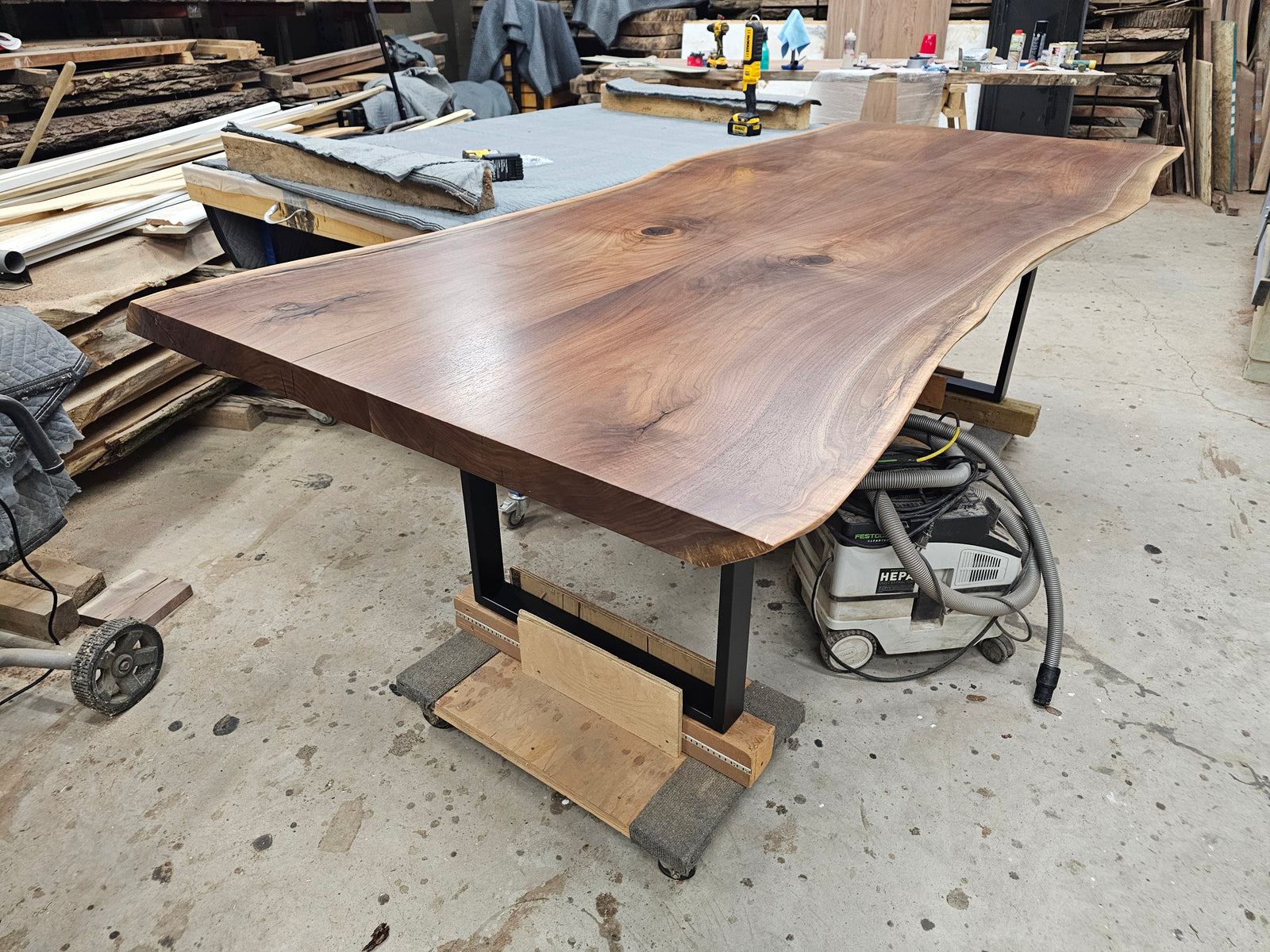 Completed bookmatched walnut dining table on inset black steel legs and temporary moving supports in the Beaver Hardwood studio.